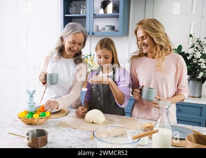 Großmutter, Mutter und Enkelin kommen zusammen, um in der gemütlichen Küche traditionelles Osterbrot für die Familientradition zu backen. Osterferien Stockfoto
