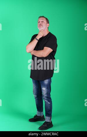 Echte Menschen, Mann in seinen 50ern, der lässige Kleidung trägt, sich auf dem grünen Bildschirm des Studios posiert, eine Vielzahl von Emotionen und Körperpositionen, voller Körper und Stockfoto