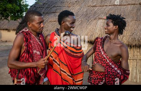 Drei männliche Maasai-Krieger, die Shukas tragen, unterhalten sich in ihrem Dorf Mikumi, Tansania Stockfoto