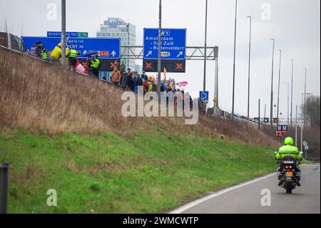 Aktivisten der Extinction Rebellion stehen während ihrer Blockade gegenüber der Autobahn A10. Extinction Rebellion, eine Blockade auf der Autobahn A10 in Amsterdam; 15 Minuten nachdem die ersten Demonstranten auf der Autobahn gelaufen waren, begann die Polizei mit Verhaftungen. Insgesamt wurden 326 Verhaftungen vorgenommen und 31 blieben in Haft. Die restlichen 295 wurden per Bus nach Amsterdam Noord transportiert und freigelassen. Kurz vor dem Polizeieinsatz wurden die Aktivisten gewarnt, dass Schlagstöcke und Pfefferspray verwendet würden, obwohl dies nicht vorkam. Die Demonstration fand am ehemaligen Hauptsitz der ING Bank statt. Stockfoto
