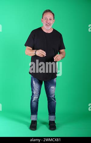 Echte Menschen, Mann in seinen 50ern, der lässige Kleidung trägt, sich auf dem grünen Bildschirm des Studios posiert, eine Vielzahl von Emotionen und Körperpositionen, voller Körper und Stockfoto