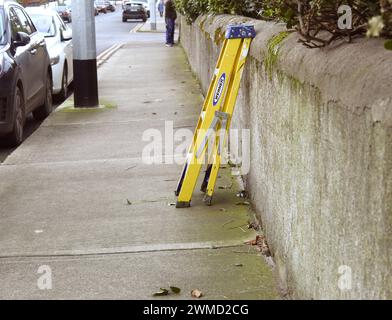 Dublin, Irland - 24. Februar 2024: Foto einer kleinen gelben Stufenleiter an einer Wand auf einem Pfad. Stockfoto