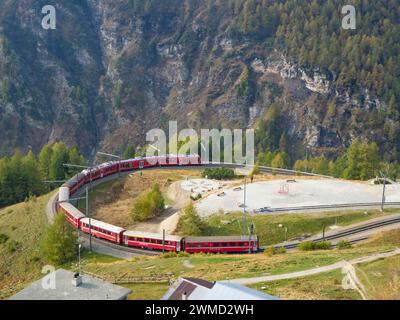 Alp Grüm, Schweiz - 14. Oktober 2023: Ein roter Zug der Rhätischen Eisenbahnen, der eine Kurve in Richtung Poschiavo fährt Stockfoto