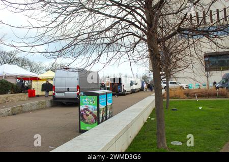 Dublin, Irland - 24. Februar 2024 Ein weites Landschaftsfoto von Lieferwagen, Mülltonnen und Leinwänden in einem Park neben einem großen Gebäude. Stockfoto