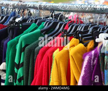 Farbenfrohe Wollpullover, die an Kleiderbügeln hängen und im Winter auf dem Markt unter freiem Himmel verkauft werden Stockfoto