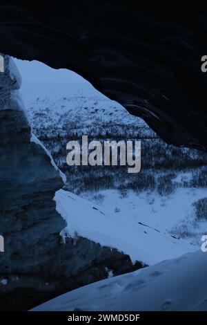 Eine Person spaziert durch eine verschneite Berglandschaft unter einer Höhle Stockfoto