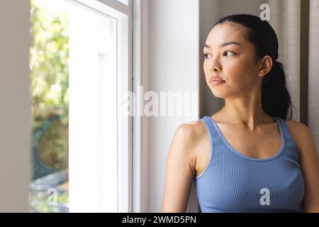 Die junge kaukasische Frau schaut nachdenklich aus dem Fenster, mit Kopierraum Stockfoto