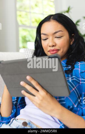 Junge birassische Frau sucht zu Hause auf einem Tablet Stockfoto