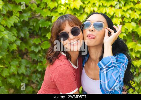 Zwei Frauen, die eine Sonnenbrille tragen, posieren im Freien spielerisch Stockfoto