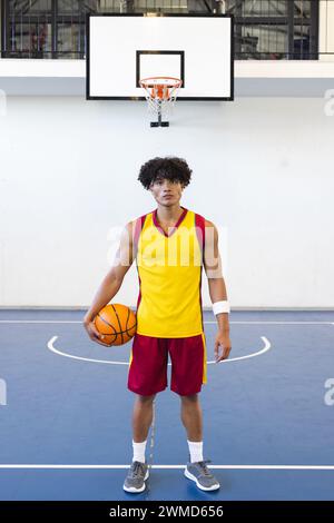 Junger birassischer Mann steht selbstbewusst auf einem Basketballfeld Stockfoto
