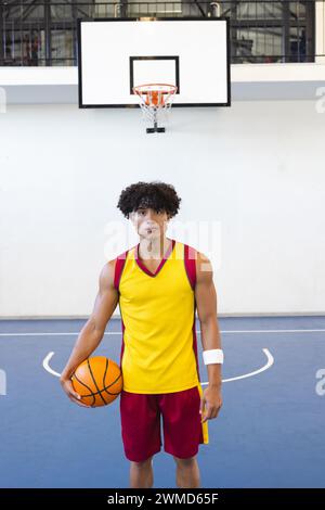 Junger birassischer Mann steht selbstbewusst auf einem Basketballfeld Stockfoto