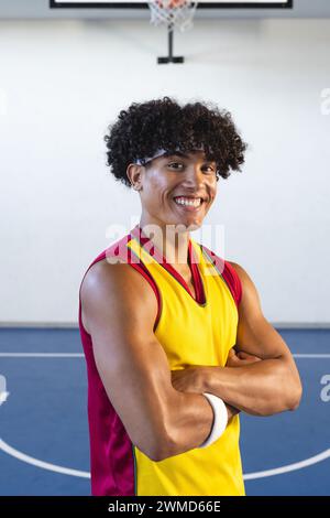 Junger birassischer Mann posiert selbstbewusst auf einem Basketballfeld Stockfoto