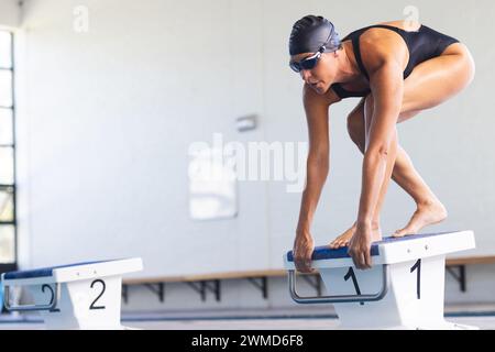 Die weibliche weibliche Sportlerin aus dem Kaukasus bereitet sich darauf vor, bei einem Wettkampf in einen Pool zu tauchen Stockfoto