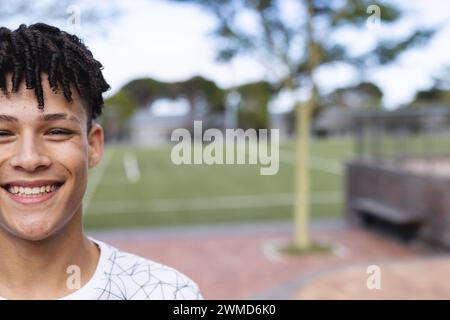 Ein birassischer Teenager lächelt auf einem Outdoor-Sportplatz an, mit Kopierraum Stockfoto