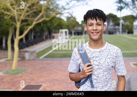 Ein birassischer Teenager lächelt auf dem Sportplatz der Highschool mit Kopierraum Stockfoto