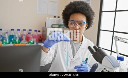 Fokussierte afroamerikanische Wissenschaftlerin bei der Analyse von Reagenzglasinhalten im modernen Laborumfeld. Stockfoto