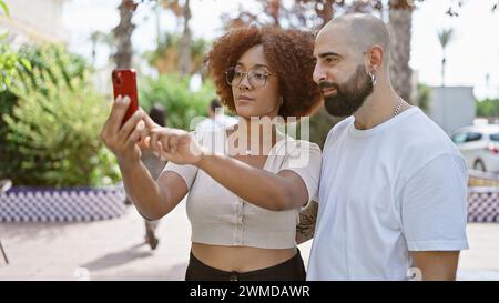 Wunderschönes Paar, das zusammen mit dem Smartphone im sonnigen Park ein Selfie macht Stockfoto