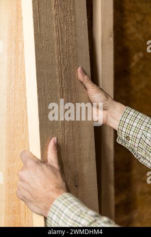 Vertikales Foto ein erfahrener Zimmermann überprüft die Qualität des Holzes in einer Werkstatt, seine Hände bewerten die Textur und Körnung für die Herstellung.Kopierraum. Busi Stockfoto