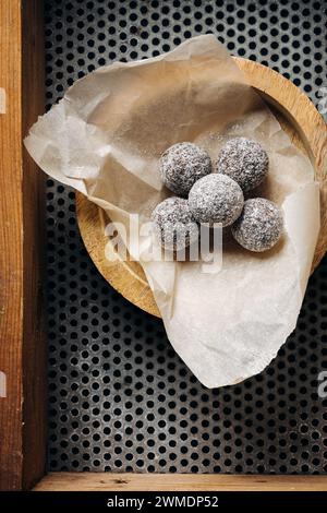 Hausgemachte Süßigkeiten in Kokosflocken auf dunklem Hintergrund. Stockfoto
