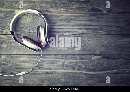 Minimalistisches Foto von Ohrhörern mit Kopierraum. Weiße dj-Kopfhörer mit Kabel auf alter Holzkulisse, flache Draufsicht. Musikkonzept Stockfoto