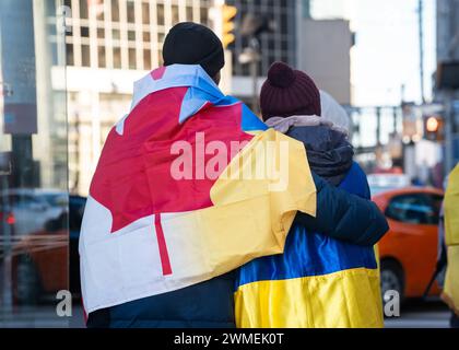 Ein Paar verlässt den Tribut mit der ukrainischen Kundgebung auf dem Nathan Phillips Square in Toronto, Kanada, die zwei Jahre seit der russischen Invasion markiert Stockfoto