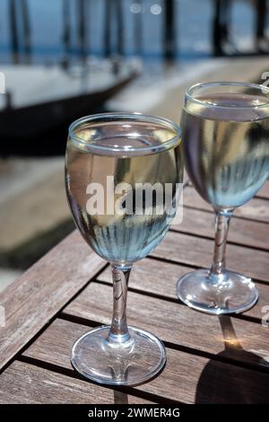 Trinken Sie Weißwein in einem Bauerncafé in einem Dorf mit Austernzucht, mit Blick auf Boote und Wasser der Bucht von Arcachon, Halbinsel Cap Ferret, Bordeaux, Frankreich in Stockfoto