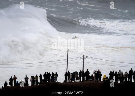 In Nazaré beobachten die Menschen eine riesige Welle. Freitag, 23. Und Samstag, 24. Februar, wurde der portugiesische Strand Praia do Norte in Nazaré von einem heftigen Sturm getroffen, der riesige Wellen schuf, für die dieser Ort weltweit berühmt ist. Die epischen Wetterbedingungen erzeugten Wellen über 20 m Höhe. (Foto: Simone Boccaccio/SOPA Images/SIPA USA) Credit: SIPA USA/Alamy Live News Stockfoto