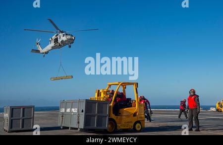 240221-N-TY639-1525 ATLANTISCHER OZEAN, Va. (21. Februar 2024) Nimitz-Klasse Flugzeugträger USS Harry S. Truman (CVN 75) Seeleute transportieren Fracht, die von einem MH-60S Sea Hawk Helikopter geliefert wird, der den 'Dragonslayers' der Helicopter Sea Combat Squadron (HSC) 11 zugeordnet ist, während einer vertikalen Auffüllung auf dem Truman-Deck, 21. Februar 2024. Truman ist das Flaggschiff der Harry S. Truman Carrier Strike Group und wird derzeit als Teil der Basisphase auf dem Weg gebracht. (Foto: Matthew Nass, Spezialist für Massenkommunikation, 2. Klasse) Stockfoto