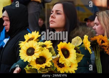 New York, New York, USA. Februar 2024. Eine ukrainische Frau hält einen Haufen Sonnenblumen bei einer Kundgebung auf dem Times Square, die das zweite Jahr seit Russlands Invasion in die Ukraine markiert. (Kreditbild: © Edna Leshowitz/ZUMA Press Wire) NUR REDAKTIONELLE VERWENDUNG! Nicht für kommerzielle ZWECKE! Stockfoto