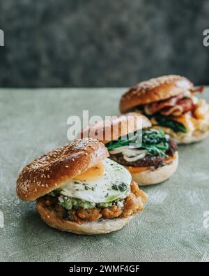 Drei Frühstückssandwiches auf einem Teller mit Bagels, Eiern, Käse und Avocado Stockfoto