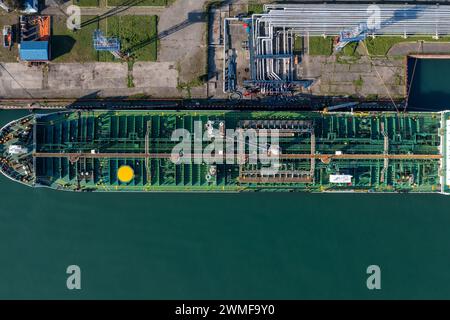 Top-down-Luftaufnahme eines großen LPG-Tankschiffes, das mit klarem blauem Wasser im Hafen angedockt ist Stockfoto