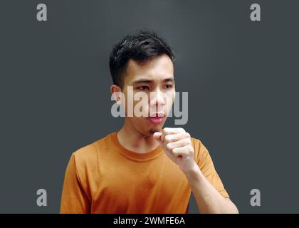 Junger asiatischer Mann hustet auf grauem Hintergrund. Kopierbereich Stockfoto