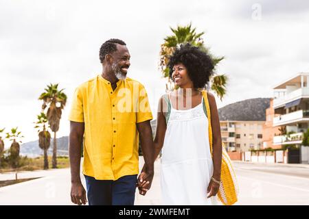 Wunderschönes reifes schwarzes Paar von Liebhabern, die sich am Meer treffen - verheiratetes afrikanisches Paar mittleren Alters, das sich im Freien verbündet und Spaß hat, Konzepte über rel Stockfoto