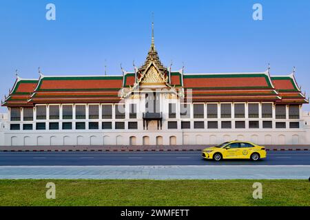 Ein gelbes Taxi fährt an der historischen Anlage des Wat Phra Kaew und dem Großen Palast vorbei, einer der wichtigsten Touristenattraktionen in Phra Nakhon, Bangkok, Thailand Stockfoto