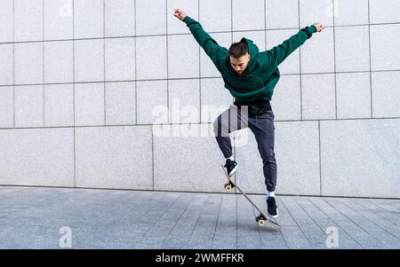 Junger Mann, der draußen in der Stadt Schlittschuhlaufen kann. Stylisches Skateboardertraining im Skatepark. Das Konzept des Skateboardens als Sport und Lebensstil. Stockfoto