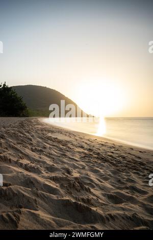 Blick über einen Strand, die Küste und das Meer bei Sonnenuntergang. Im Vordergrund der leere Sandstrand Grande Anse, Basse Terre, Guadeloupe, Französische Antillen Stockfoto