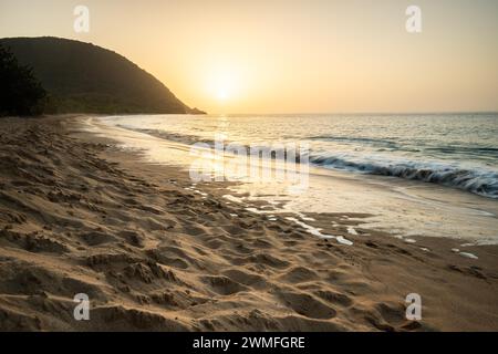 Blick über einen Strand, die Küste und das Meer bei Sonnenuntergang. Im Vordergrund der leere Sandstrand Grande Anse, Basse Terre, Guadeloupe, Französische Antillen Stockfoto