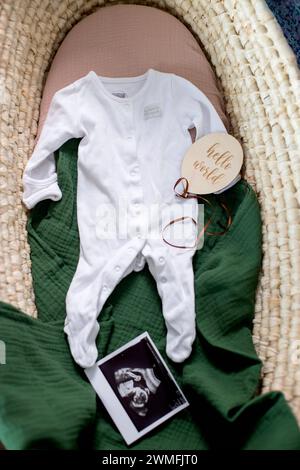 Draufsicht auf Babykleidung und Ultraschallfoto im moses Korb. Wir erwarten ein neues Leben. Vorbereitung auf das Neugeborene-Konzept. Stockfoto