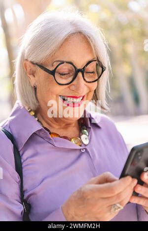 Ältere Frau lächelt glücklich mit dem Handy Stockfoto