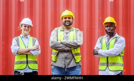 Die Hafenarbeiter stehen vor einem roten Container in einem Logistikterminal Stockfoto