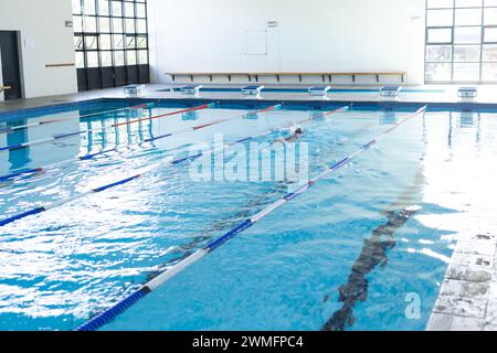 Ein einsamer Schwimmer übt in einem Hallenbad mit Kopierraum Stockfoto