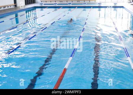 Die Person übt das Schwimmen in einem durchsichtigen Hallenbad mit Kopierraum Stockfoto