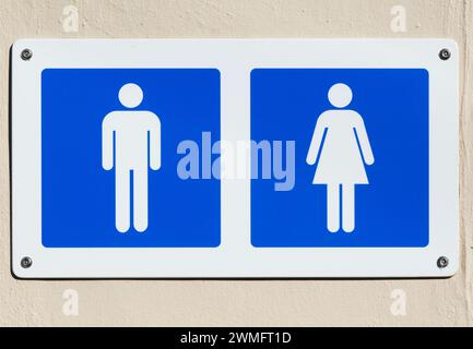 Weiße männliche und weibliche Figuren auf blauem Hintergrund ausschneiden, öffentliche Toiletten Schild UK Stockfoto