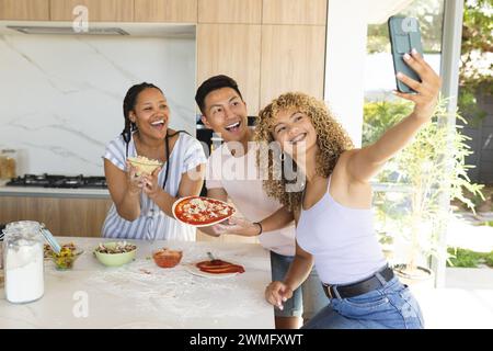 Ein junger asiatischer Mann und zwei rassistische Frauen machen ein Selfie in einer Küche Stockfoto
