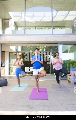 Ein junger asiatischer Mann und zwei junge Frauen üben Yoga zu Hause Stockfoto