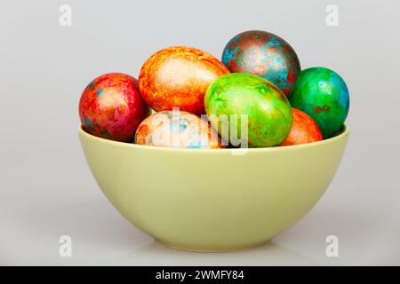 Bunte handbemalte ostereier in einer pastellfarbenen Keramikschale auf grauem Hintergrund Stockfoto