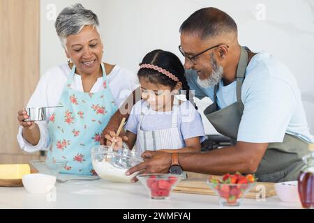 Birassische Großeltern und Enkelinnen backen gerne gemeinsam in einer Küche Stockfoto