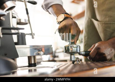 Der afroamerikanische Barista bereitet Kaffee in einem Café zu Stockfoto