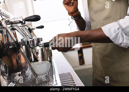 Ein afroamerikanischer Barista bereitet Kaffee an einer Espressomaschine zu Stockfoto