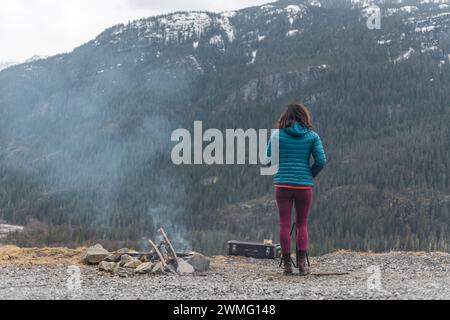 Frau spielt Saxophon in den Bergen neben dem Feuer Stockfoto